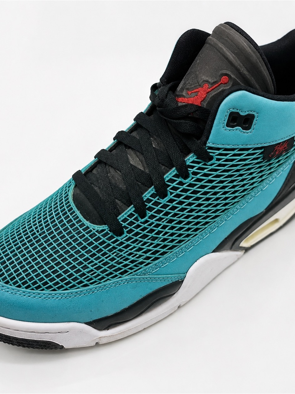 Teal and black Jordan athletic sneakers with red Jumpman accents and black laces